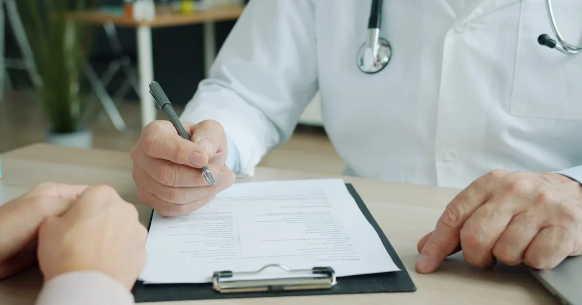 A doctor writing on a patient's chart